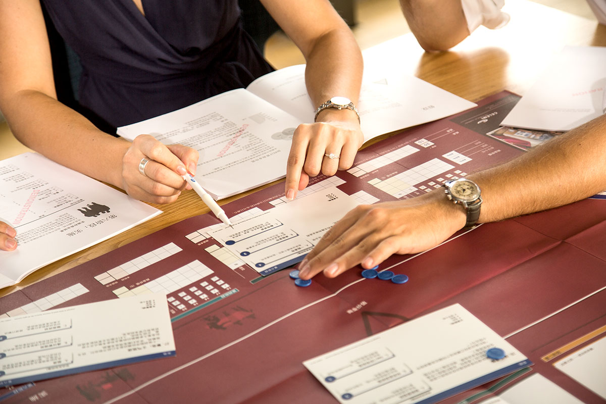 Close-up of moving tokens on physical board of CELEMI Cayenne™ business simulation