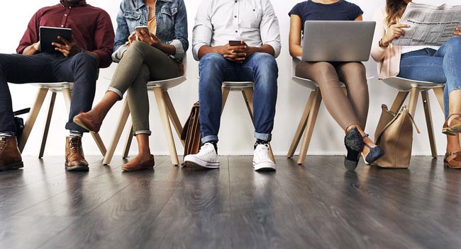 People sitting with electronic devices in a waiting room