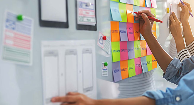 Team writing on sticker notes attached to a whiteboard